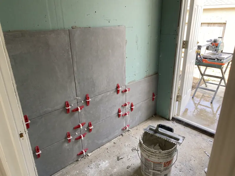 Large porcelain tile going up a shower wall with leveling clips