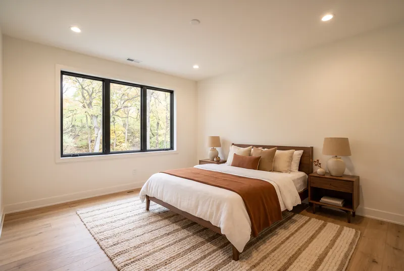 Lower level guest bedroom with a walnut bed and a large window looking out at a wooded ravine