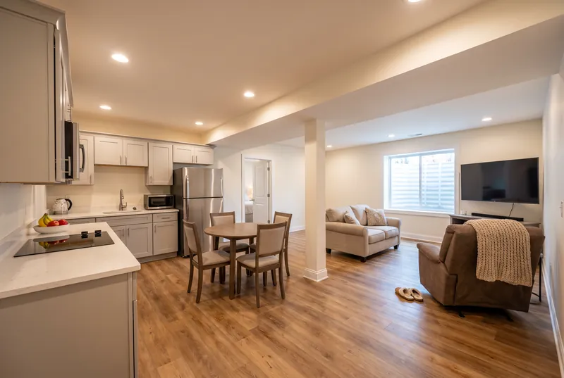 After: Basement in law suite with a kitchenette, small dining table, loveseat and an egress window