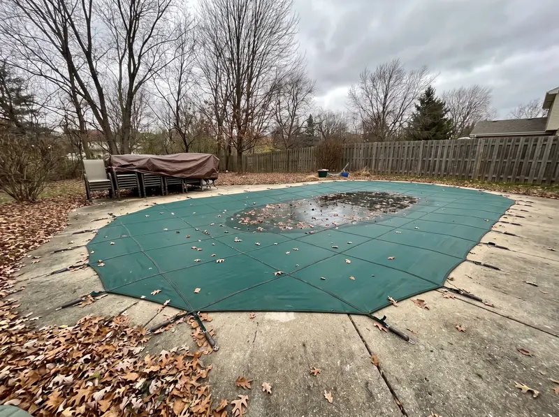 Inground pool closed for winter under a mesh safety cover